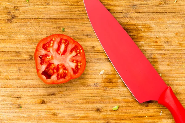 Single beefsteak tomato sliced in half with knife — Stock Photo, Image