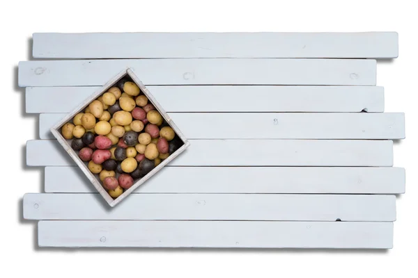 Colorful potatoes in box on wooden planks — Stock Photo, Image