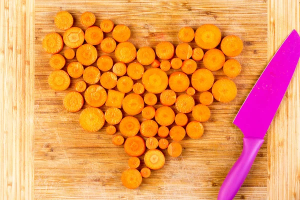 Chopped carrots as heart shape beside knife — Φωτογραφία Αρχείου