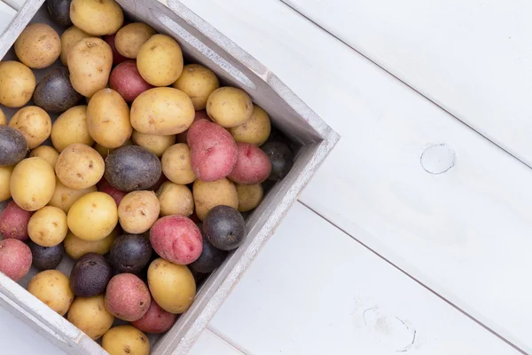 Wooden box with multicolored baby potatoes — Stock Photo, Image