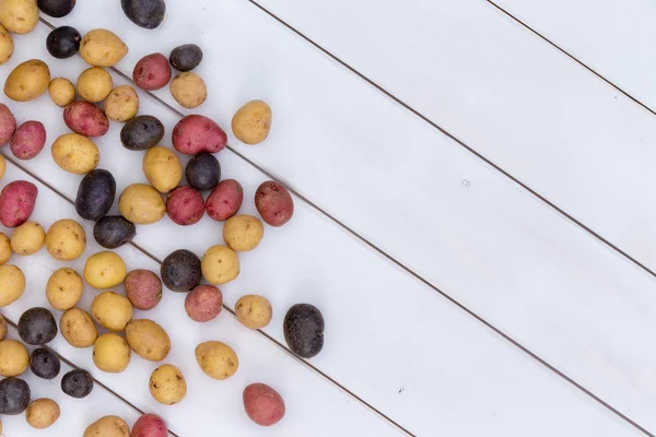 Разбросанная свежая разноцветная детская картошка — стоковое фото