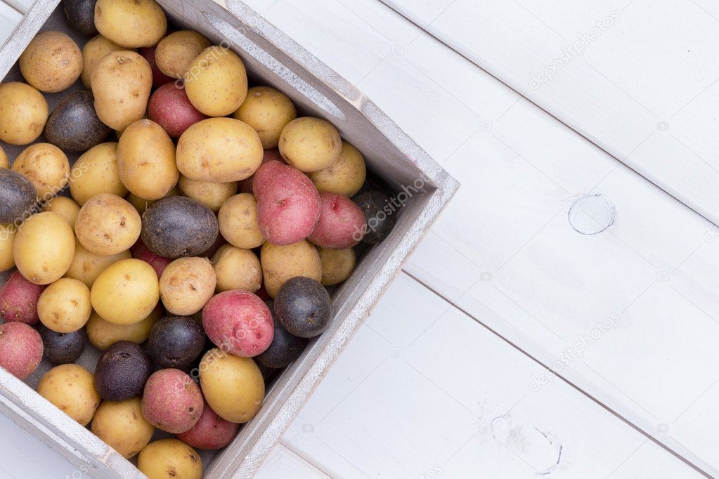 Wooden box with multicolored baby potatoes
