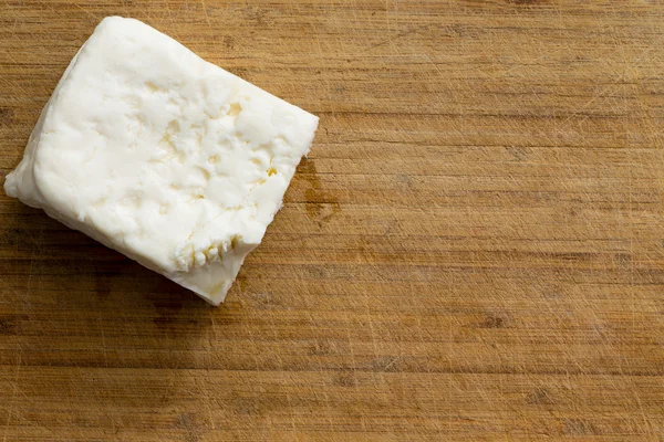 Cubo de queijo branco na tábua de corte — Fotografia de Stock