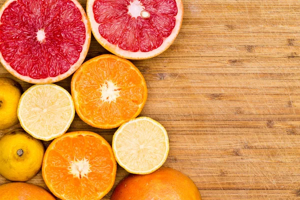 Pompelmoes, sinaasappelen en citroenen gesneden op hout — Stockfoto