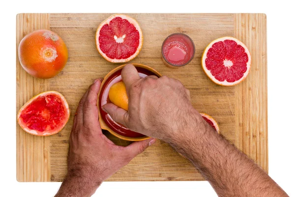 Hombre exprimiendo mitades de pomelo rubí —  Fotos de Stock