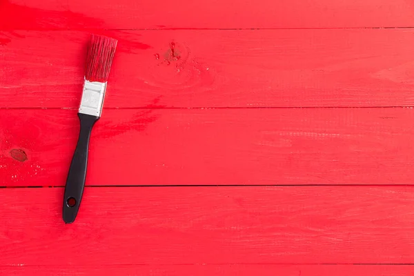 Bright red painted wooden surface with brush — Stock Photo, Image