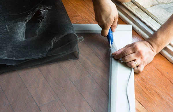 Man replacing ripped old patio door screen — Stock Photo, Image