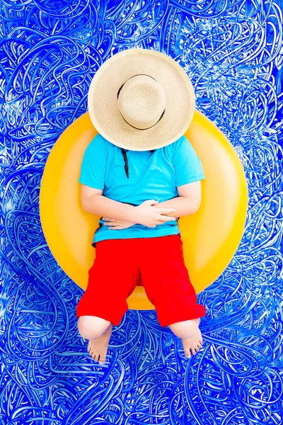 Счастливый мальчик отдыхает на тюбике в бассейне — стоковое фото