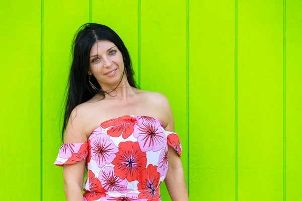 Trendy brunette woman against a green wall — Stock Photo, Image