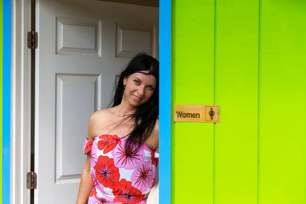 Mujer joven y bonita apoyada en la puerta de un baño — Foto de Stock