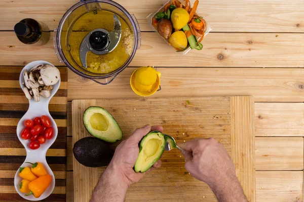 Hände eines Mannes, der eine Avocado-Birne aushöhlt — Stockfoto