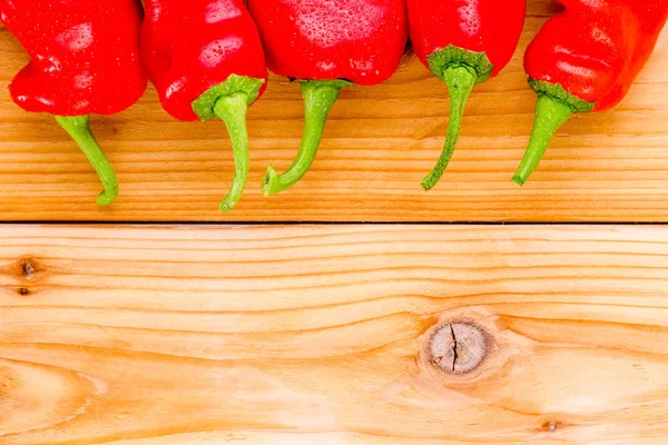 Border of red hot cayenne chili peppers on wood — Stock Photo, Image