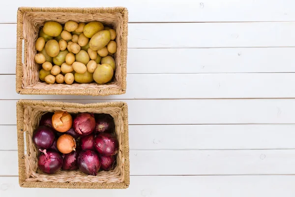 Dos cestas de mimbre con patatas frescas y cebollas — Foto de Stock