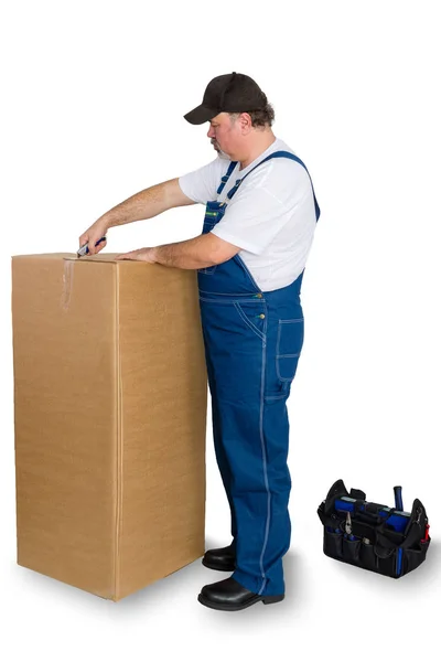 Man wearing dungarees unboxing large cardboard box — Stock Photo, Image