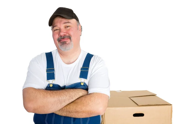 Smiling delivery man standing against big box — Stock Photo, Image