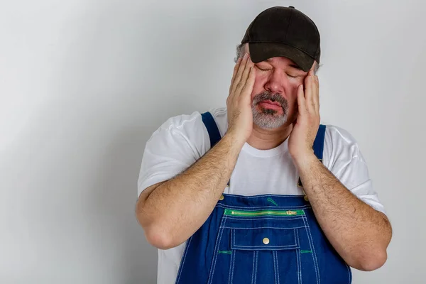 Worker in overalls with a bad headache — Stock Photo, Image