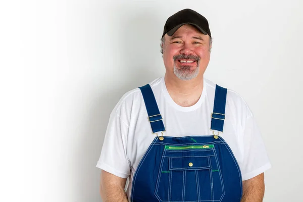 Sorrindo homem vestindo dungarees com boné — Fotografia de Stock