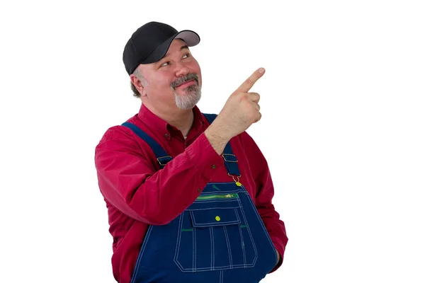 Smiling worker in dungarees pointing upwards — Stock Photo, Image