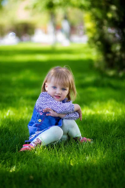 Il bambino si siede in un'erba — Foto Stock
