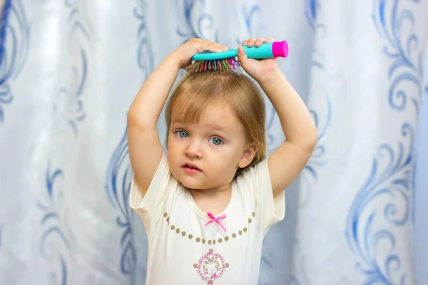 Het kleine meisje borstels het haar met een haarborstel — Stockfoto