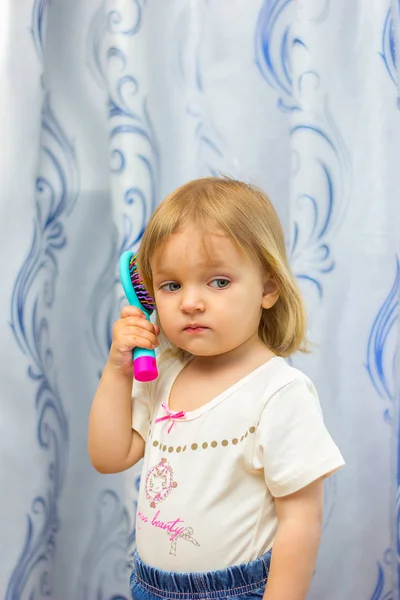 Het kleine meisje kamt haar een haarborstel — Stockfoto