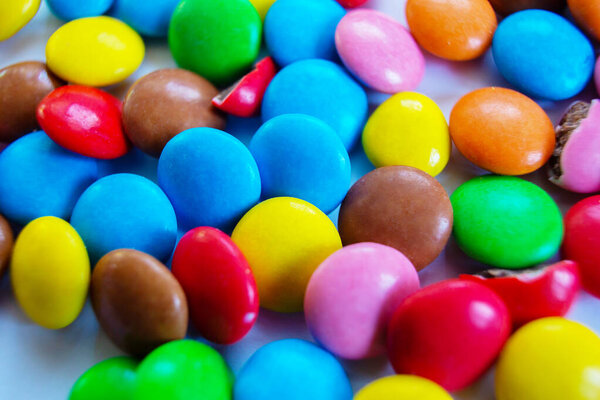 Many multi-colored small round candy pills are scattered on the table.