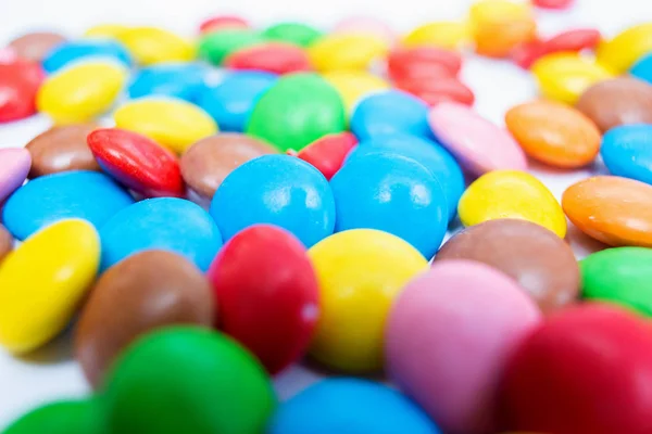 Muitas pílulas de doces redondas pequenas e multicoloridas estão espalhadas na mesa de close-up — Fotografia de Stock