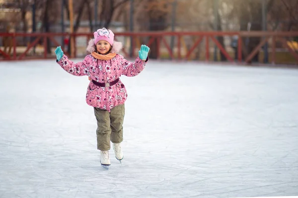 Menina alegremente monta patins de figura em uma pista de gelo no inverno — Fotografia de Stock