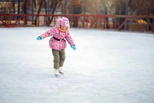 Menina incerto fica em patins figura em uma pista de gelo e tenta montar — Fotografia de Stock