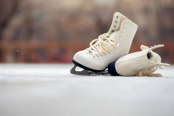 Um par de patins de figura branca jaz em uma pista de gelo aberta — Fotografia de Stock