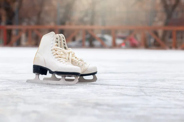 Un par de patines blancos están parados en una pista de hielo abierta. Deportes de invierno — Foto de Stock