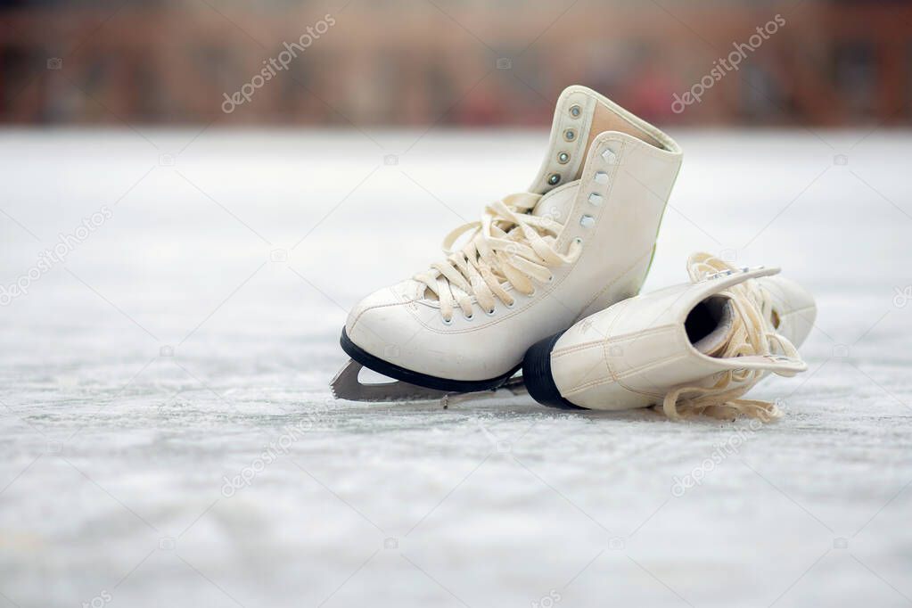 A pair of White Figure Skates lie on an open ice rink