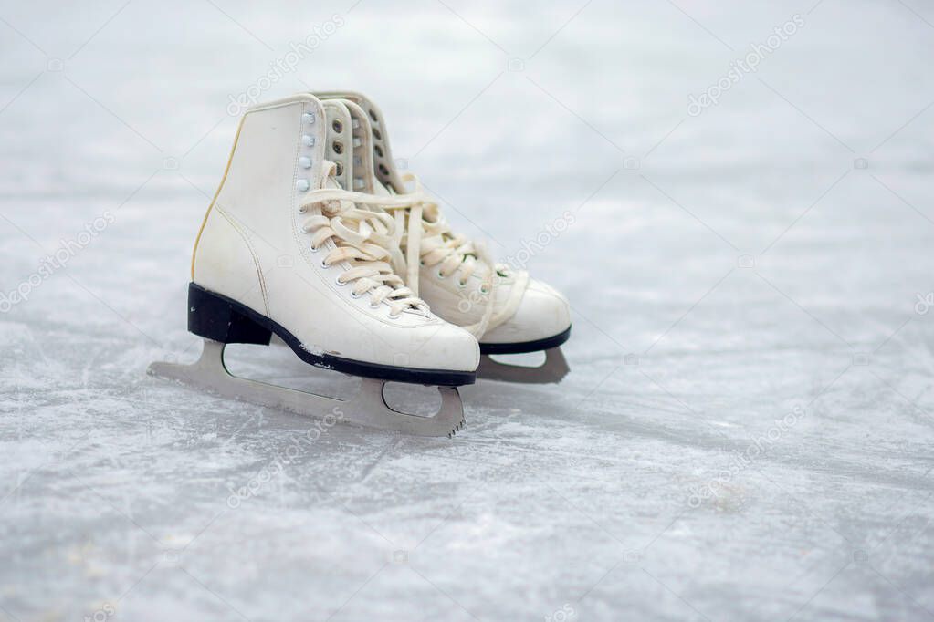 A pair of White Figure Skates are standing on an open ice rink. Winter sport