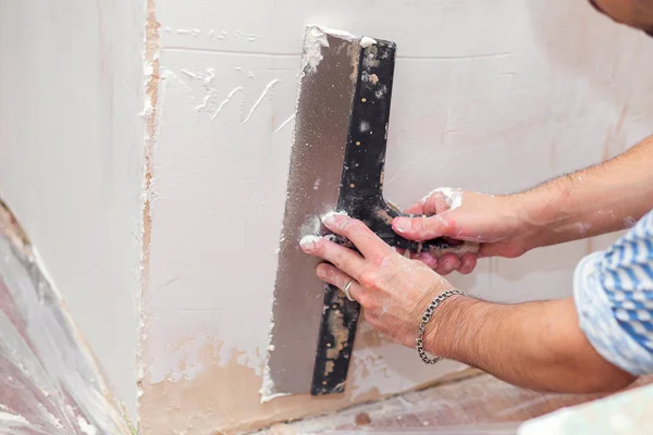 Repair of the living quarters. Putty interior walls with a wide metal spatula — Stock Photo, Image