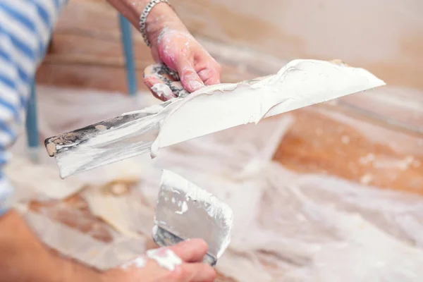 Worker puts putty on a spatula for plastering internal walls in a living room — 스톡 사진