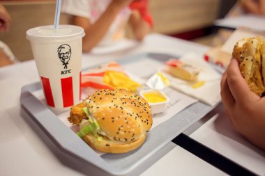 KFC restoran zincirlerinden birindeki fast food seti. Tepside pipetle hamburger ve içecek. Fast food