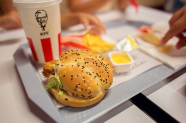KFC restoran zincirlerinden birindeki fast food seti. Bir kafede aile yemeği. Hamburger, içecek ve sos.