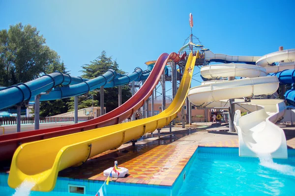 Hautes glissières en plastique multicolores sous forme de tuyaux tourbillonnants dans le parc aquatique — Photo