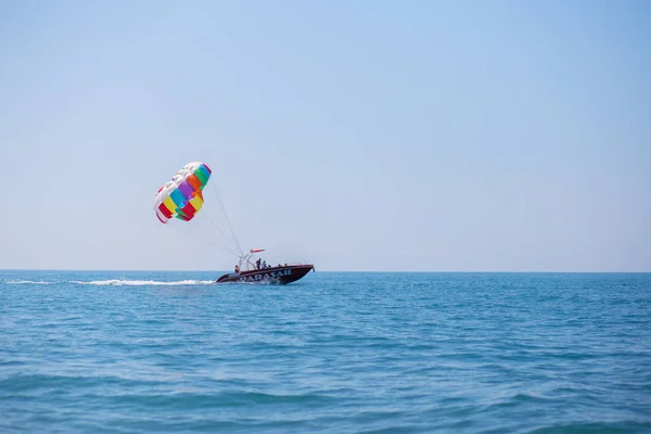 Fallschirmspringen mit Touristen von einem Boot mitten im Meer. Reisespaß am Strand — Stockfoto