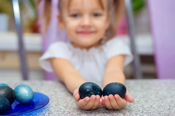 Маленькая милая девочка держит пасхальные яйца на ладонях — стоковое фото