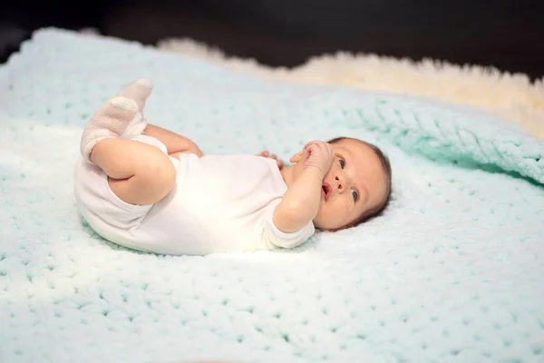 Pequeno bebê recém-nascido em um terno branco jaz em um sofá em casa — Fotografia de Stock