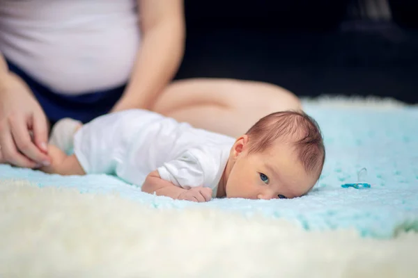 Jovem mãe coloca seu bebê recém-nascido em sua barriga no sofá — Fotografia de Stock