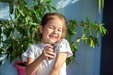 Beyaz tişörtlü bir kız elinde bir Moğol faresini tutuyor ve ona sarılıyor. Çocuklar ve hayvanlar