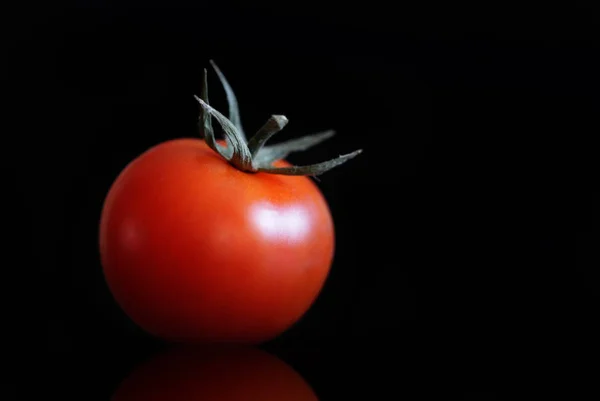 Tomaat op een zwarte achtergrond met reflectie — Stockfoto