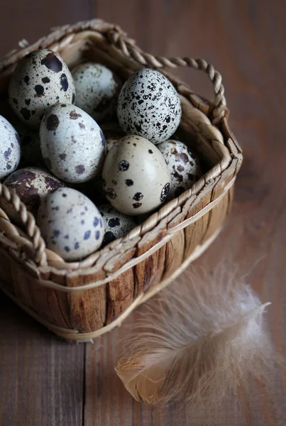 Ovos de codorna em uma cesta em uma superfície de madeira — Fotografia de Stock
