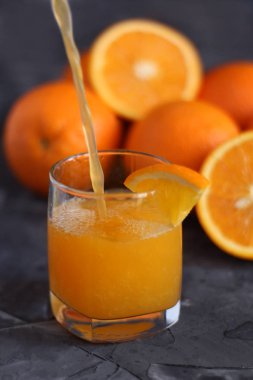 Portakal suyu bir bardak ve bir beton zemin üzerine portakal