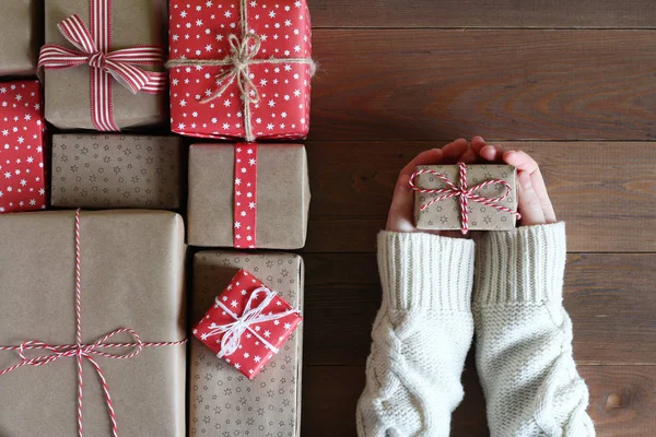 Les mains féminines dans un pull gardent un cadeau sur une surface en bois — Photo