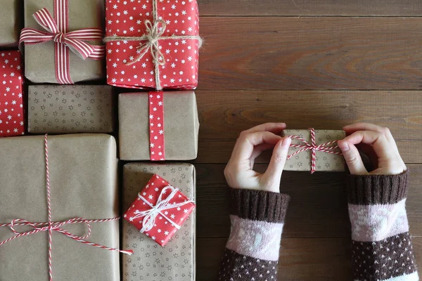Female hands in a sweater keep a gift on a wooden surface — Stock Photo, Image