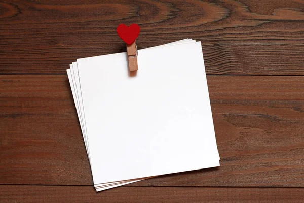 Pile of papers with a wooden clothespeg with red heart on a wooden table