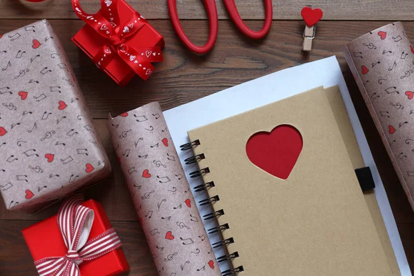 Packing a notebook with heart in gift paper to St. Valentine\'s Day